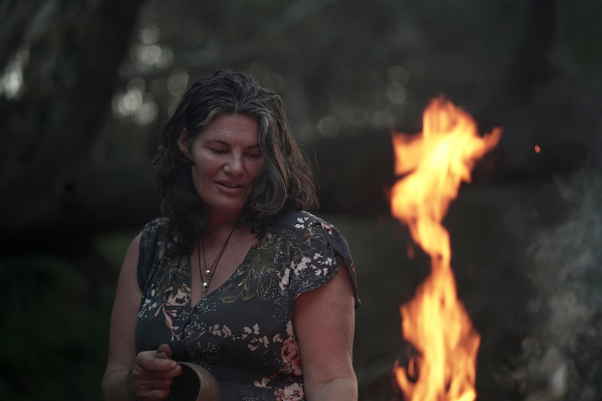 A woman stands next to a fire