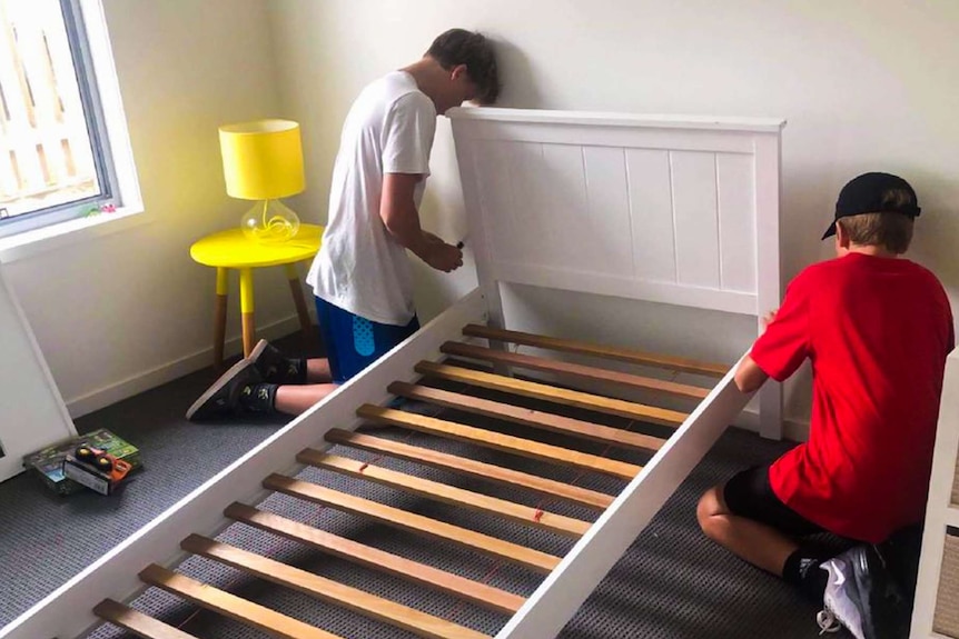 Two boys assembling a bed.