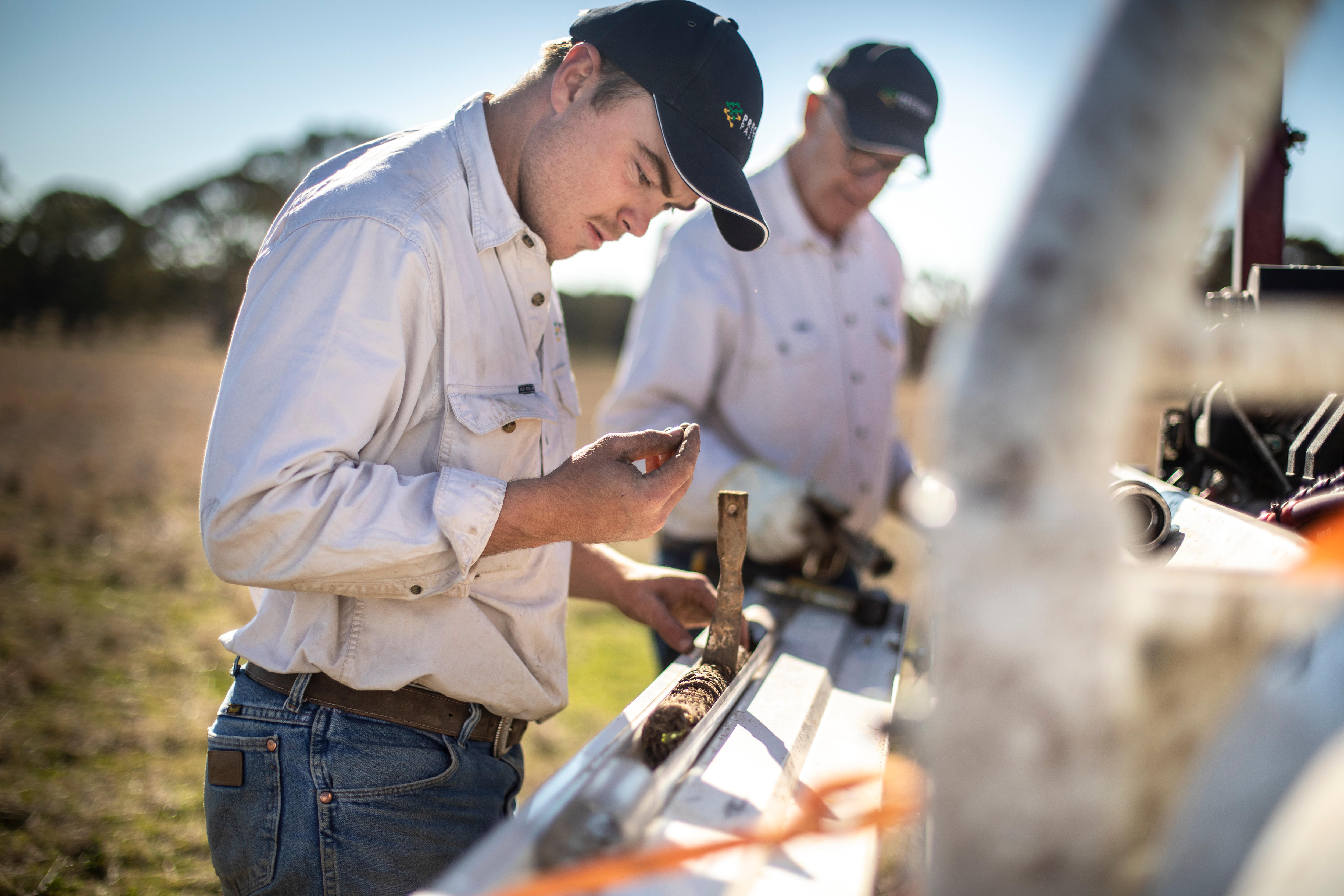 A man stands next to a tray of soil on the back of a ute