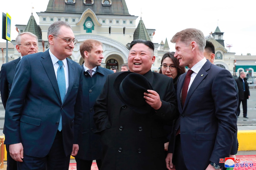 Kim Jong Un laughs surrounded by Russian officials in Vladivostok.