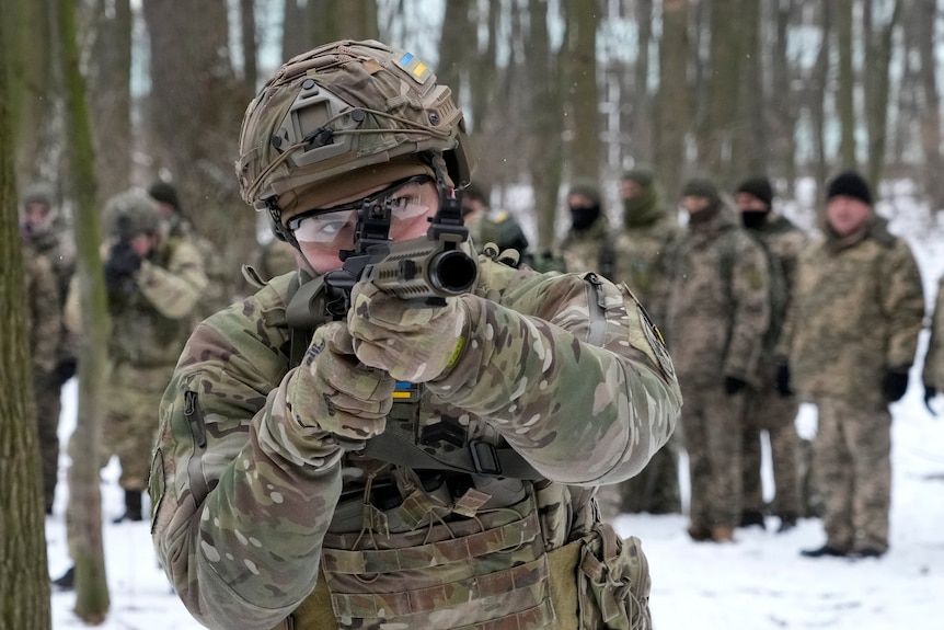 Un membre des Forces de défense territoriale ukrainiennes pointe une arme sur la caméra.