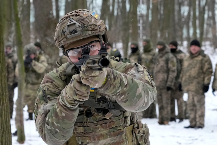 A members of Ukraine's Territorial Defense Forces points a gun at the camera.