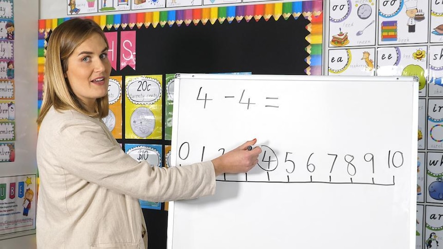 Female teacher points to number line on whiteboard