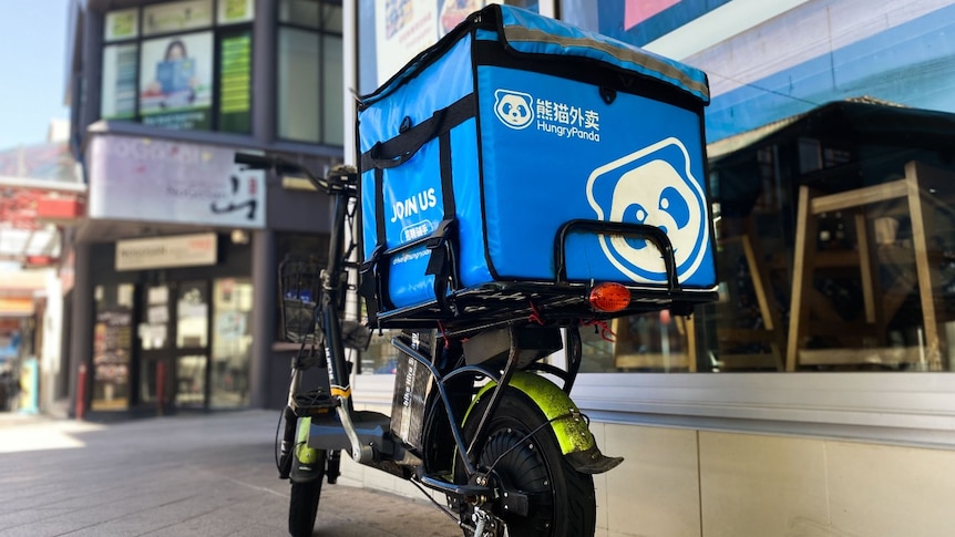 A motorcycle with food delivery bag on the back that reads: Hungry Panda