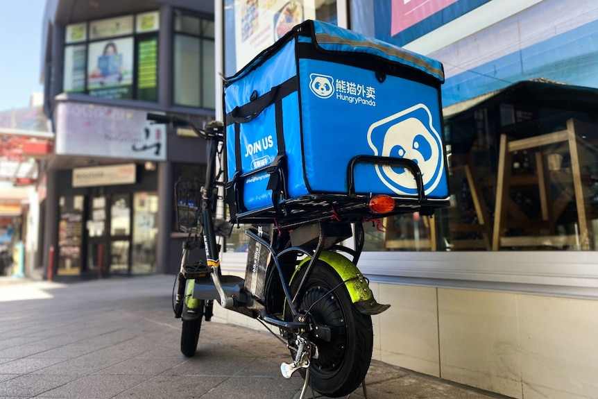 A motorcycle with food delivery bag on the back that reads: Hungry Panda