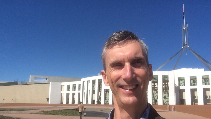 Selfie of a man standing in front of Parliament House in Canberra