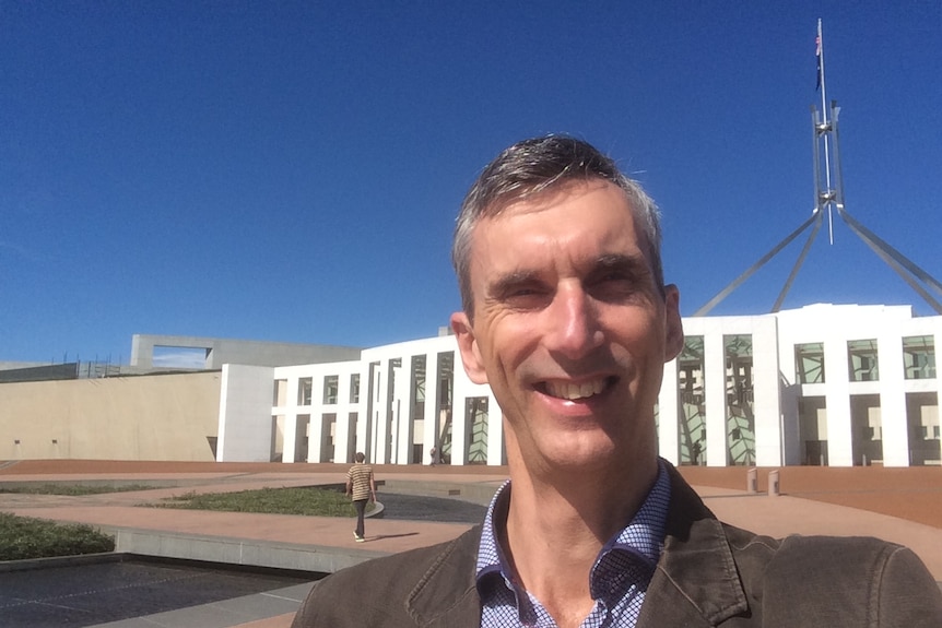 Selfie of a man standing in front of Parliament House in Canberra