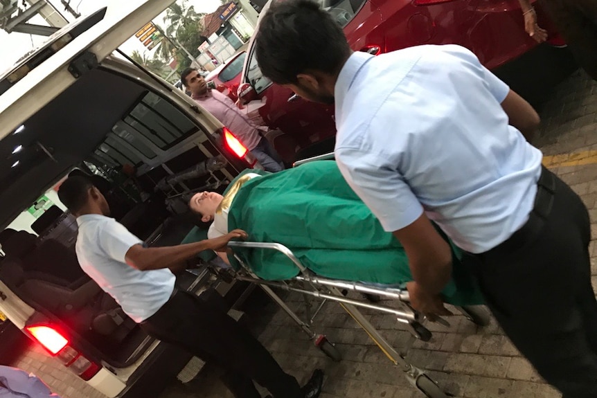 A young white woman is wheeled into an ambulance on stretcher bed