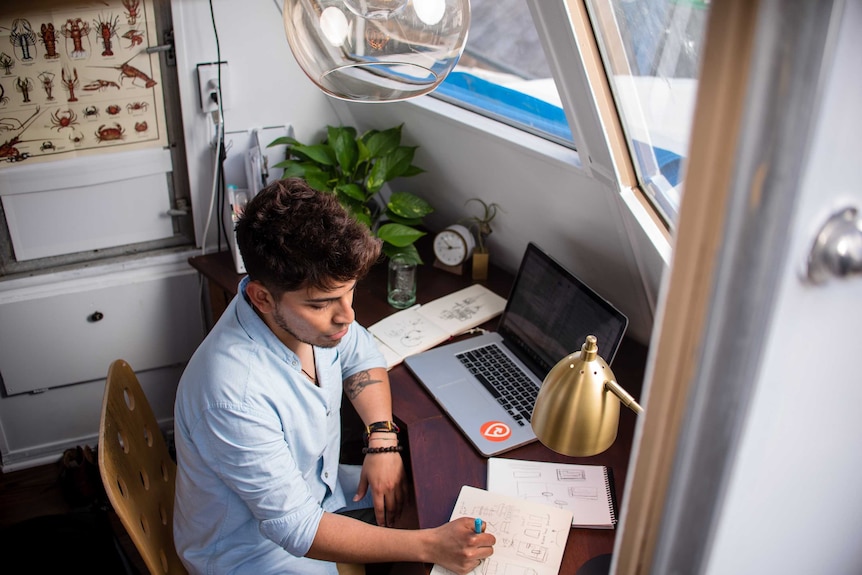 Man works on a computer in a home office space in a story about tax deductions you can claim if you work from home.