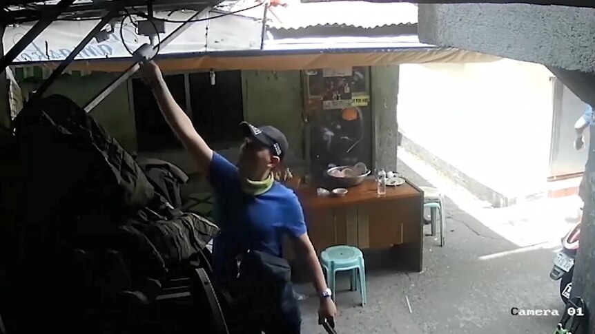 A police officer moves a CCTV camera.