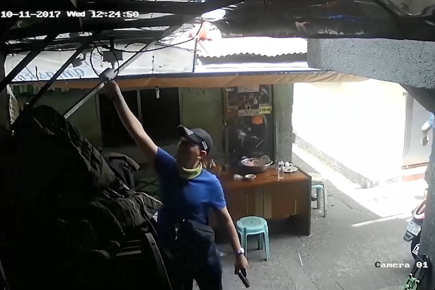 A police officer moves a CCTV camera.