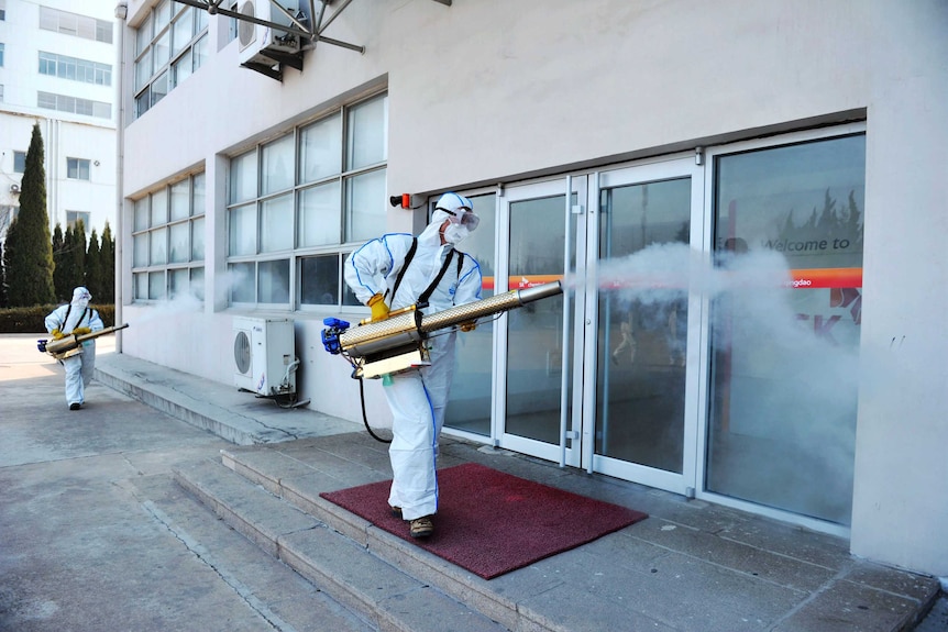 Workers in protective suits spray disinfectant at a business in China.