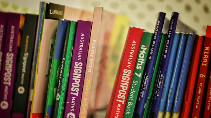 A row of maths books on a shelf.