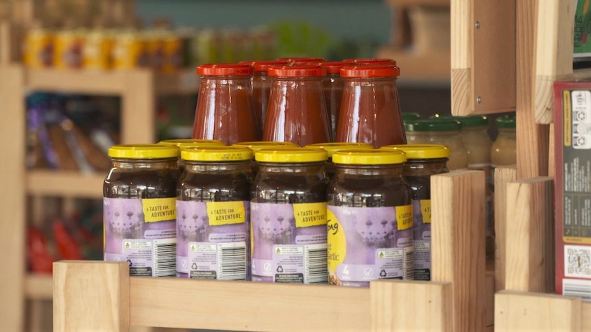 Bottled sauces sit on a shelf.
