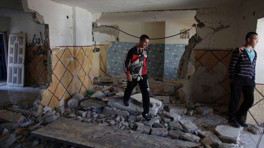 Relatives of Abdel-Rahman Shaloudi walk through his destroyed home
