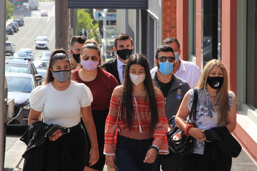 A group of people wearing masks walking up a path.