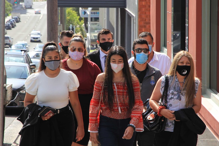 A group of people wearing masks walking up a city street.