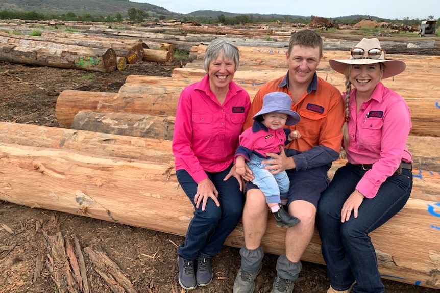 The Pershouse family sit on timber logs at their sawmill.