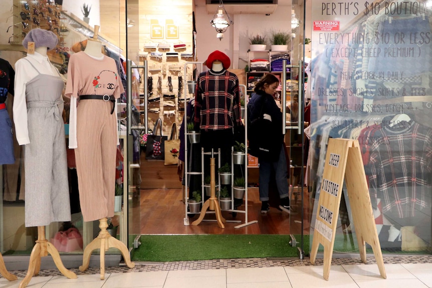 A shop front with clothes on mannequins out the front.