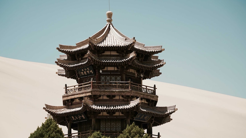 An intricately carved tower sits beside an oasis in the Gobi Desert.