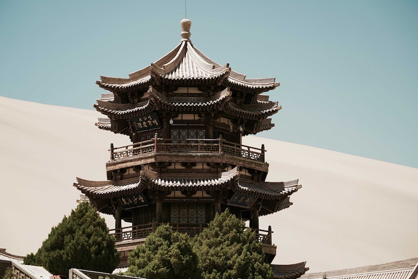 An intricately carved tower sits beside an oasis in the Gobi Desert.