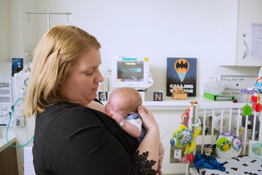 Bree Ackley cuddles her son Grayson amongst the medical machines in the neonatal intensive care unit.
