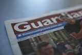 A close up shot of a newspaper with the title "Guardian" in focus.