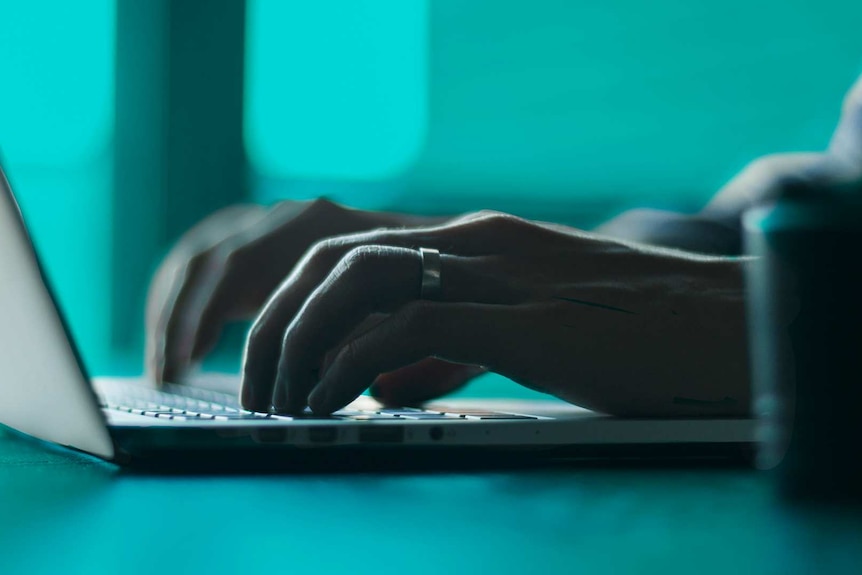 Close-up of hands typing on keyboard to depict online stalking.