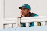 Coach Justin Langer watches a cricket game from the team's balcony.