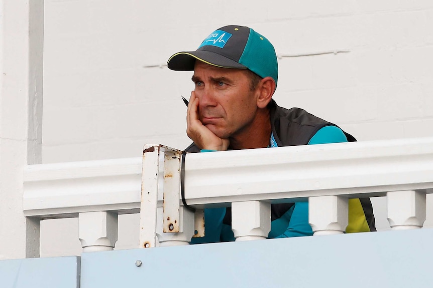 Coach Justin Langer watches a cricket game from the team's balcony.