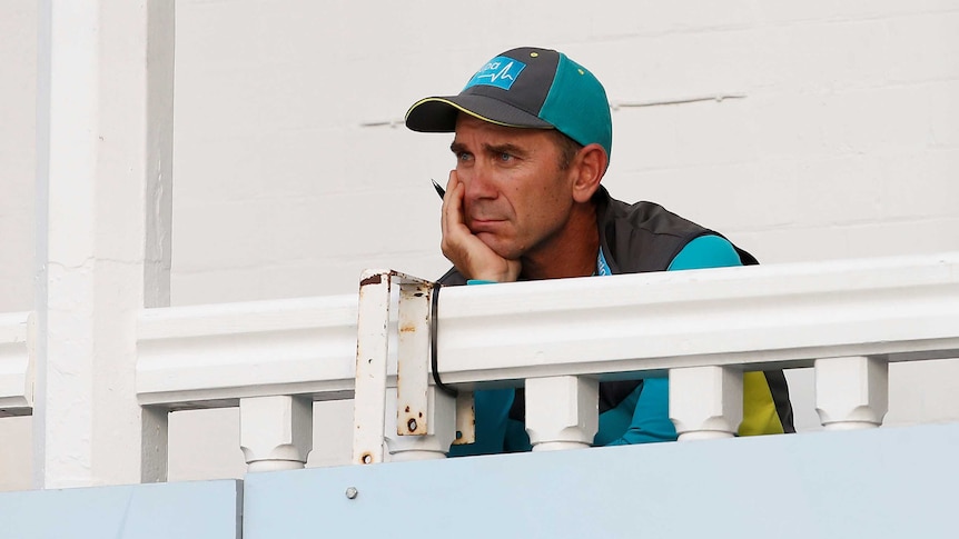 Coach Justin Langer watches a cricket game from the team's balcony.