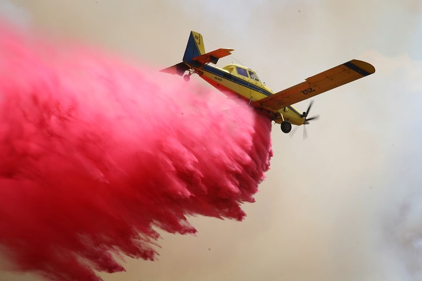 A plane dropping red fire retardant.