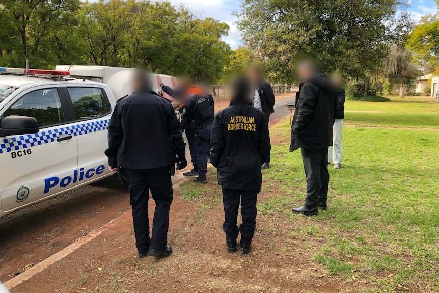 A man in an orange shirt being arrested by Police and the Australia Border Force.