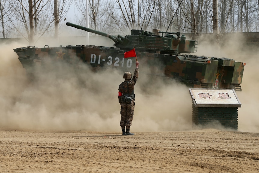 A soldier of China's People's Liberation Army with a tank during a military promotional event.