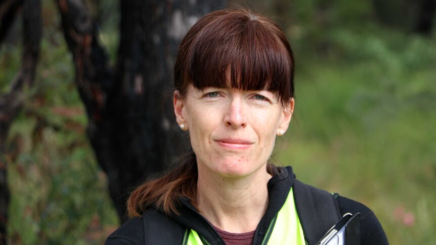 Murdoch University biologist Dr Rachel Standish looks at the camera, wearing hi-vis and holding a clipboard.