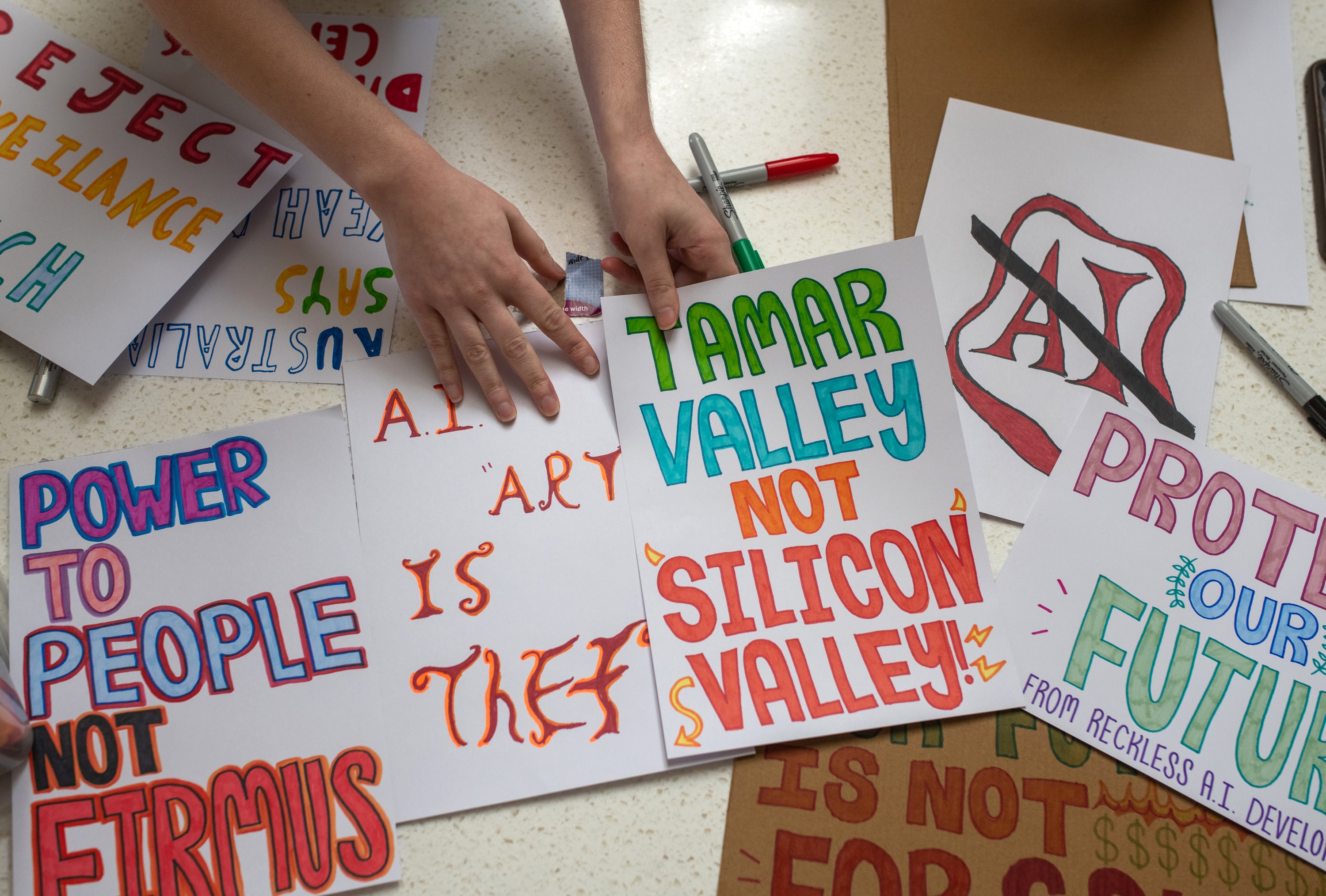 Close-up angle of colourful hand drawn posters protesting AI data centres and AI in general.