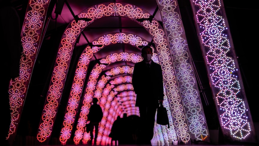 silhouettes of people can be seen in a tunnel of pink lights in Tokyo, Japan