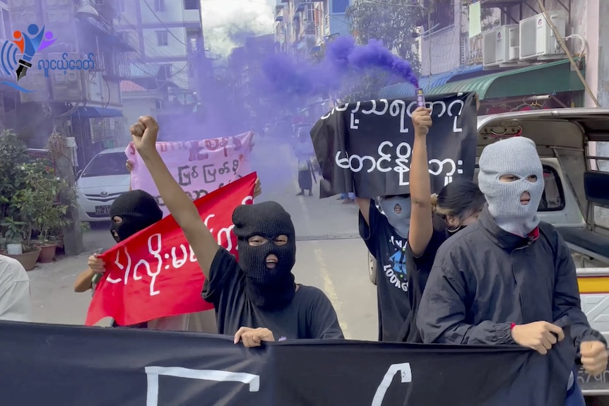 Masked protesters walk the streets with signs following the executions of four activists 