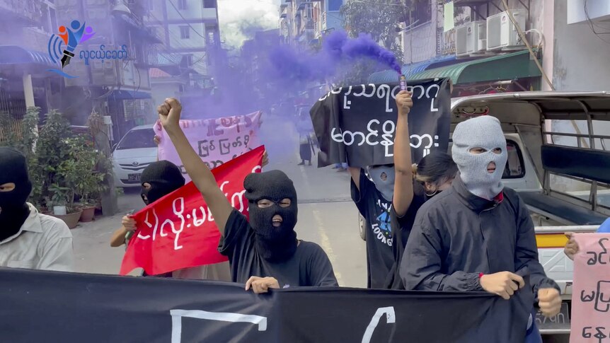 Masked protesters walk the streets with signs following the executions of four activists 