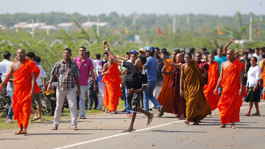 A Sri Lankan protester hurls a stone at government supporters during a protest in Mirijjawila village in Ambalantota, Sri Lanka, Saturday