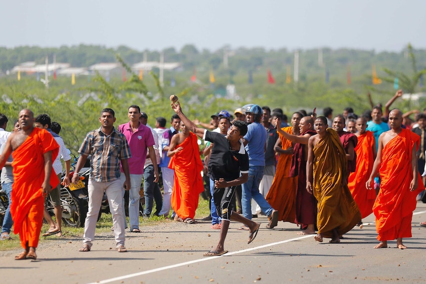 A Sri Lankan protester hurls a stone at government supporters during a protest in Mirijjawila village in Ambalantota, Sri Lanka, Saturday