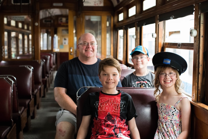 Simon Tye and his family sit in an old tram
