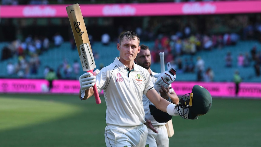An Australian batsman waves his bat at the crowd as he walks off after an unbeaten Test century.