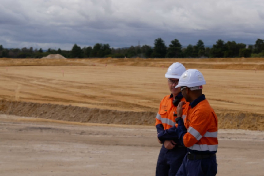 Two construction workers stand on the site of a proposed lithium refinery