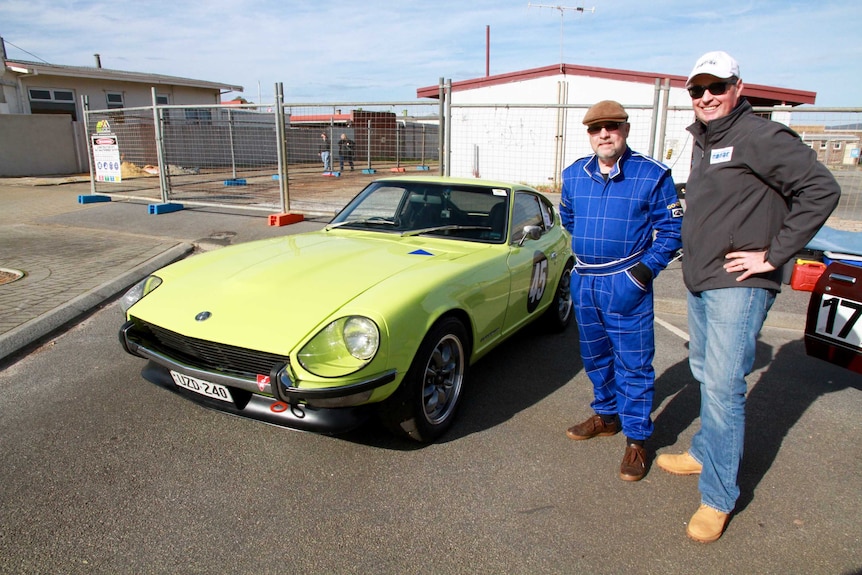 Two men stand beside a lime-green 1972 Datsun 240Z