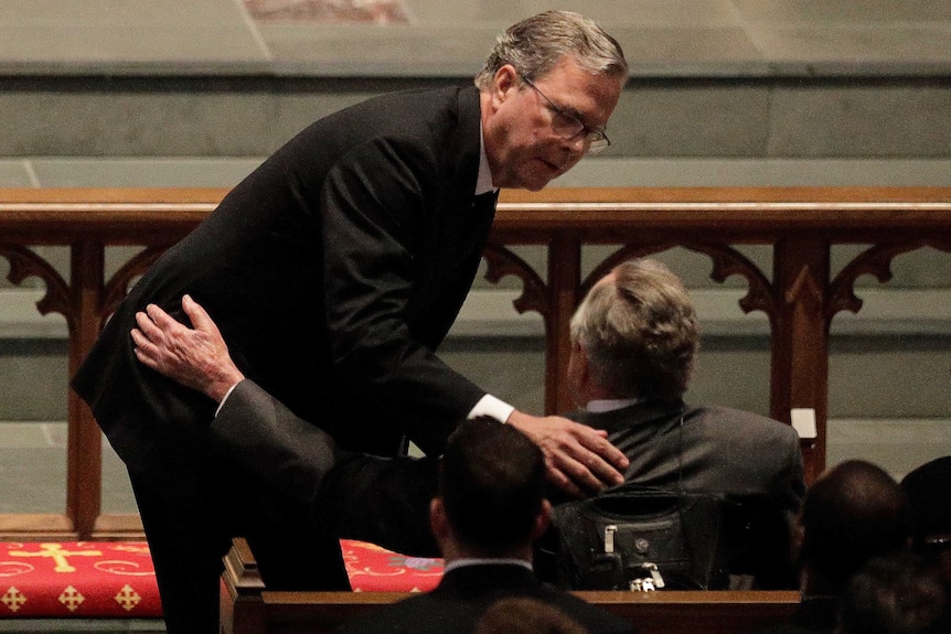 Jeb Bush leans down to comfort his father, former president George HW Bush.