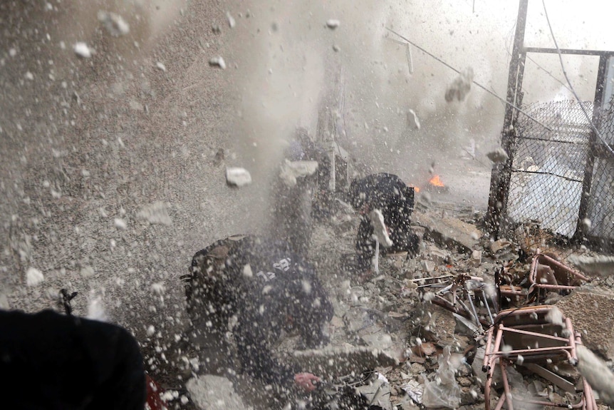 Free Syrian Army fighters run for cover as a tank shell explodes on a wall next to them.