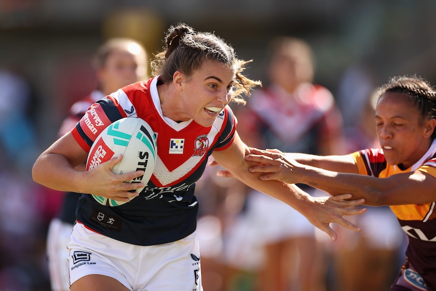 An NRLW player breaks a tackle 
