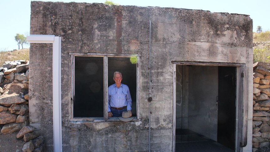 WIde shot of man looking through the window of the bunker
