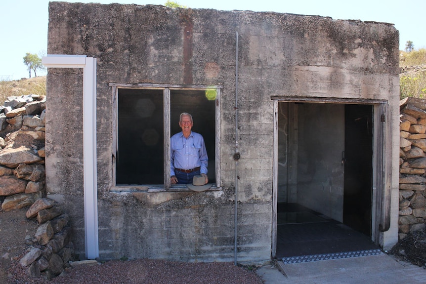 WIde shot of man looking through the window of the bunker